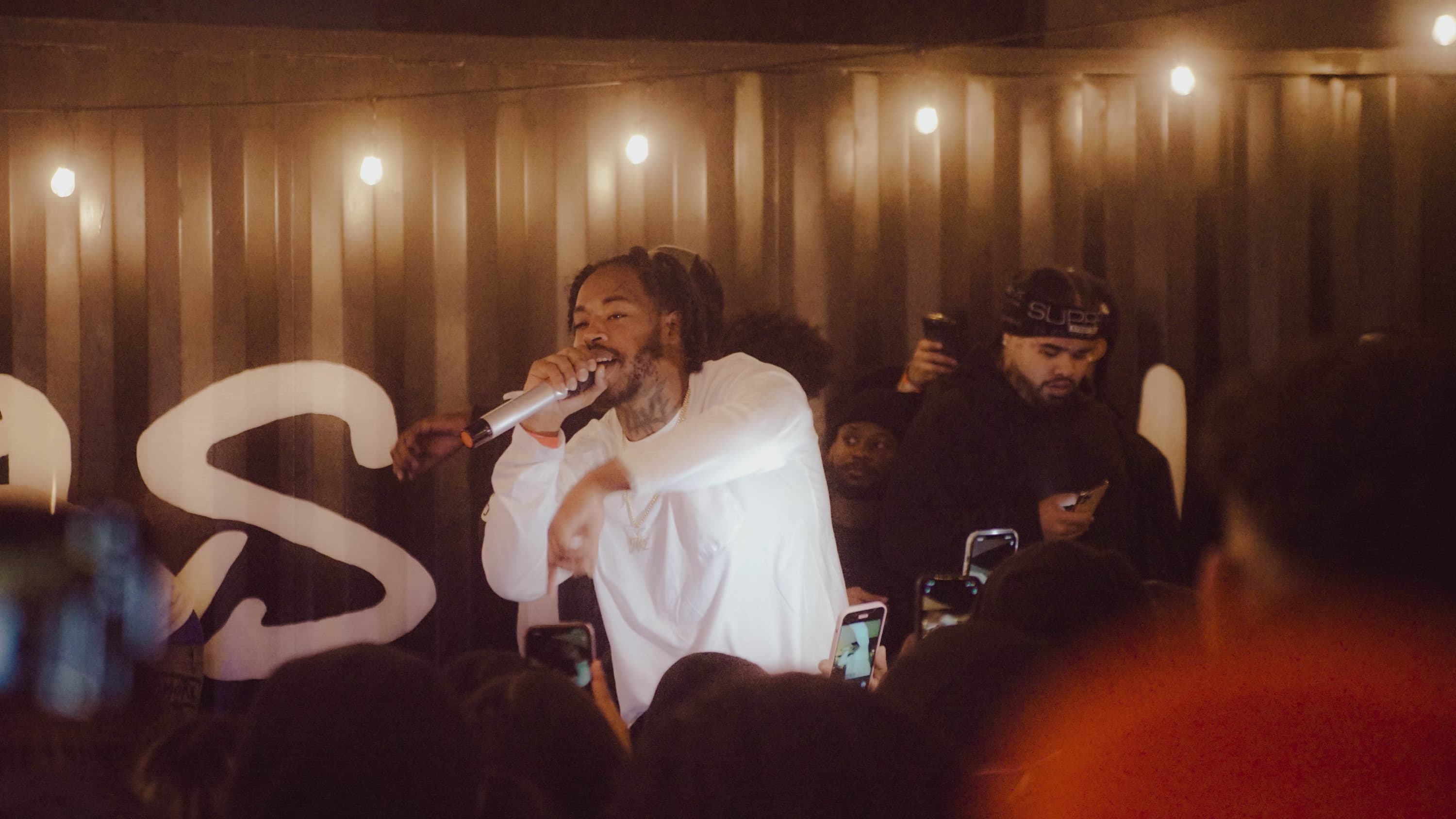 1TakeQuan performing with a microphone under warm stage lights